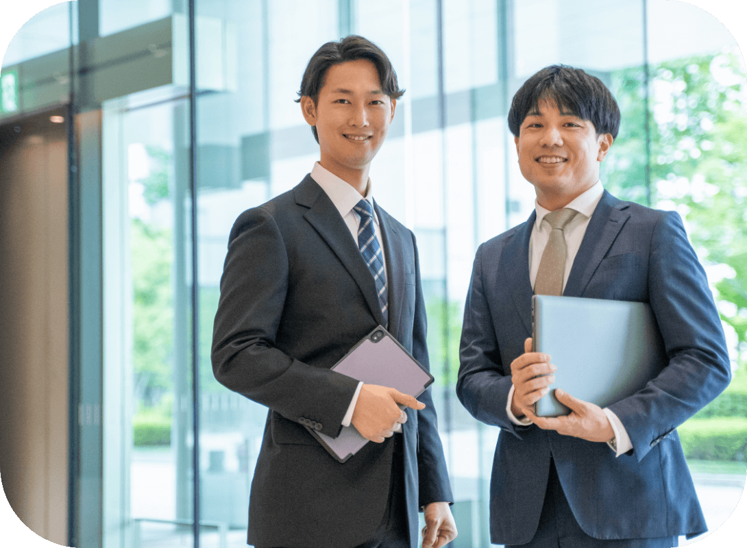 笑顔で立っているスーツ姿の男性社員2名